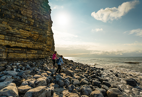 Two people walking along the pebbles in the Vale of Glamorgan)
